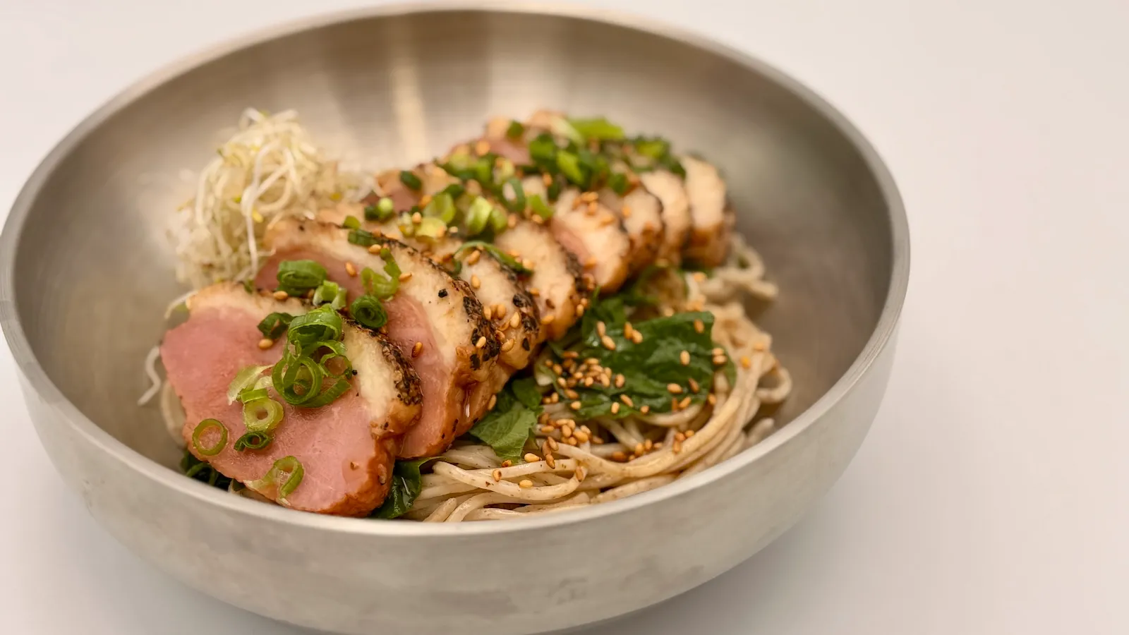 低温調理した鴨肉をのせた香り高い創作まぜそば「エゴマ油の鴨肉混ぜそば」を器に盛った様子