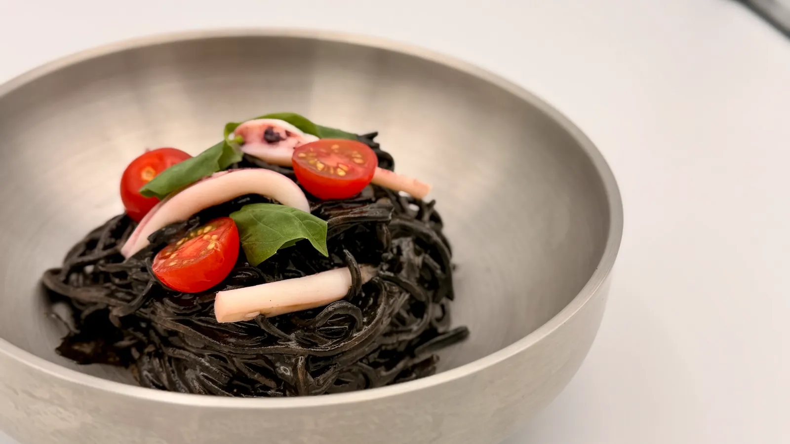 黒いイカスミソースで仕上げたソバックスのイカスミ冷麺を器に盛った様子